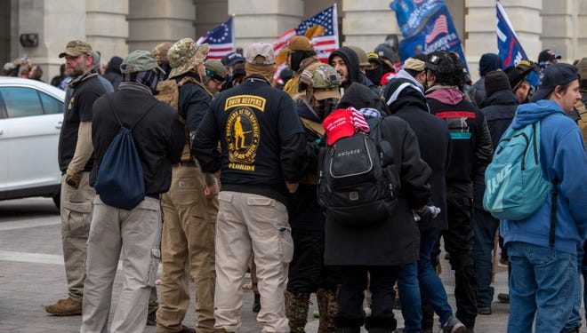 A group of men, some of whom are wearing "Oath Keepers" insignia, gathers as rioters storm the U.S. Capitol in Washington on Jan. 6.