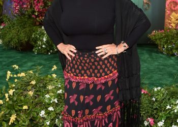 A woman standing and smiling with her hands on her hips.