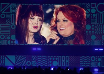 A screen projecting two women singing together