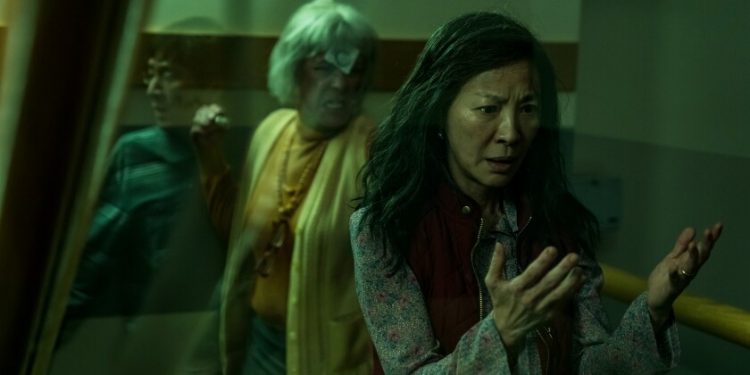 Michelle Yeoh looks at her hands as Jamie Lee Curtis raises a fist in "Everything Everywhere All At Once."