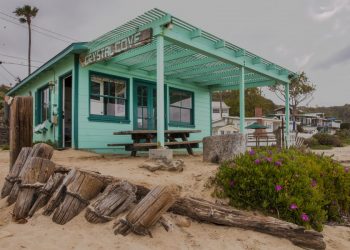 A green beach cottage with a sign that reads "Crystal Cove."