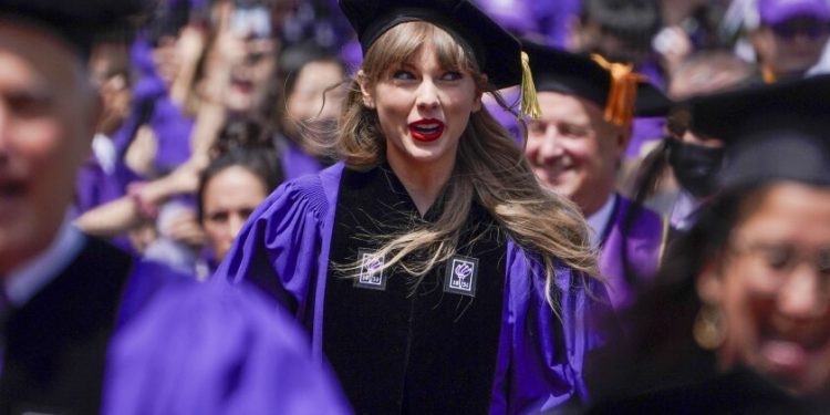 A blond woman wearing a velvet black graduation cap and purple graduation gown in a crowd