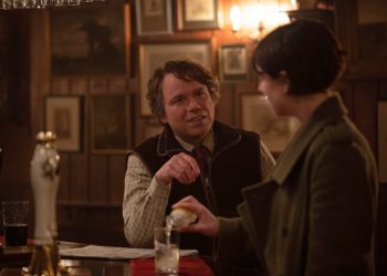 A man, right, talks to a woman pouring herself a drink at a bar