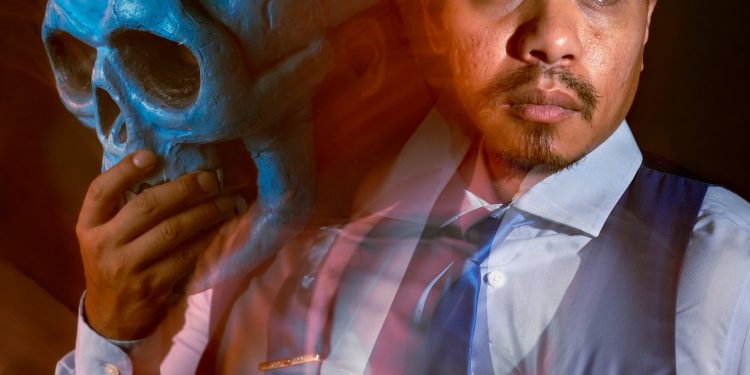 A long exposure image of a man holding a skull mask.