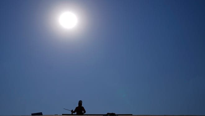 A roofer works in a housing development while the sun beats down on him during a June 2021 heat wave in Phoenix.