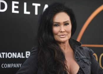 A woman with long dark hair in a black jacket on a red carpet