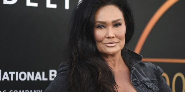 A woman with long dark hair in a black jacket on a red carpet