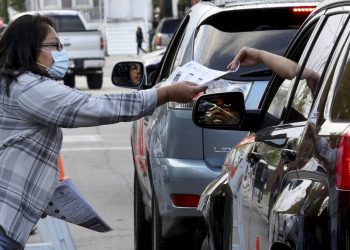 Veronica Rico, representing the Brighton Park Neighborhood Council, hands out information sheets to parents sharing concerns with student-based budgeting outside Brighton Park Elementary School in Chicago on Sept. 19, 2022. That was the Chicago Public Schools’ 20th day of class, the official date when enrollment is used to calculate the next year's school budget.