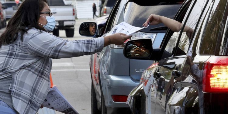 Veronica Rico, representing the Brighton Park Neighborhood Council, hands out information sheets to parents sharing concerns with student-based budgeting outside Brighton Park Elementary School in Chicago on Sept. 19, 2022. That was the Chicago Public Schools’ 20th day of class, the official date when enrollment is used to calculate the next year's school budget.